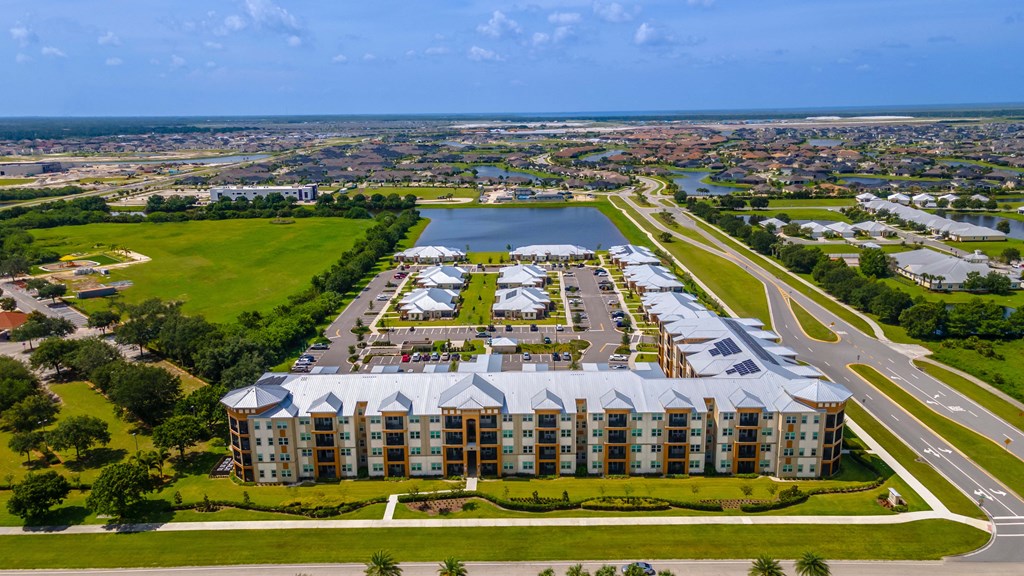 an aerial view of an apartment complex with a body of water and a city in the background