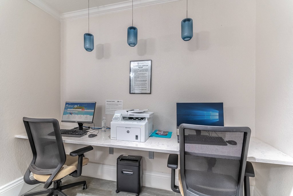 two desks with two computers and two chairs in an office