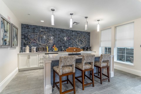 a kitchen with a bar and chairs in front of a blue brick wall