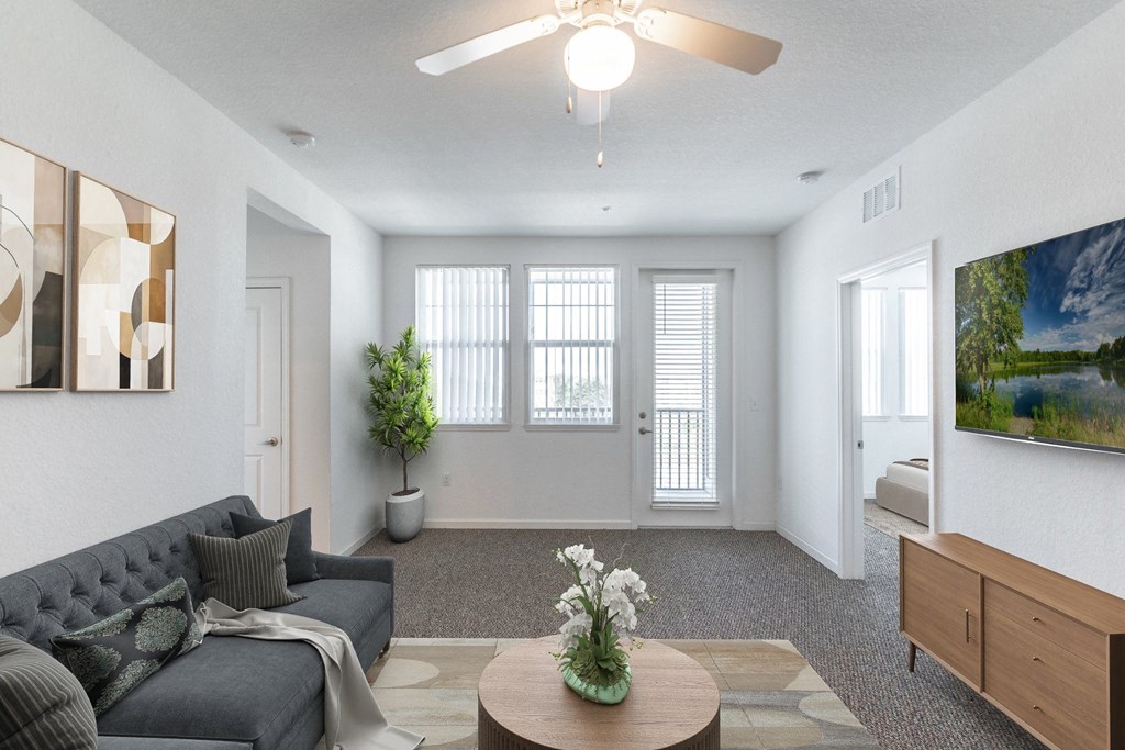 a living room with white walls and a ceiling fan