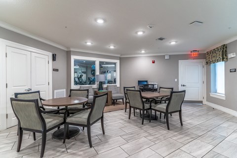 a community room with tables and chairs and a kitchen