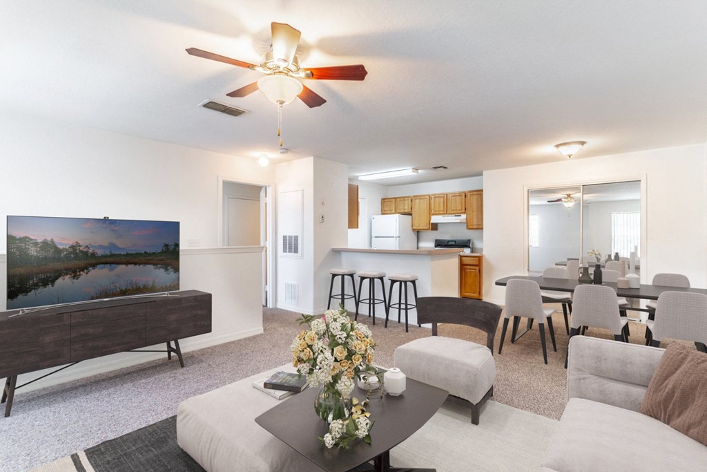 a living room with a ceiling fan and a flat screen tv