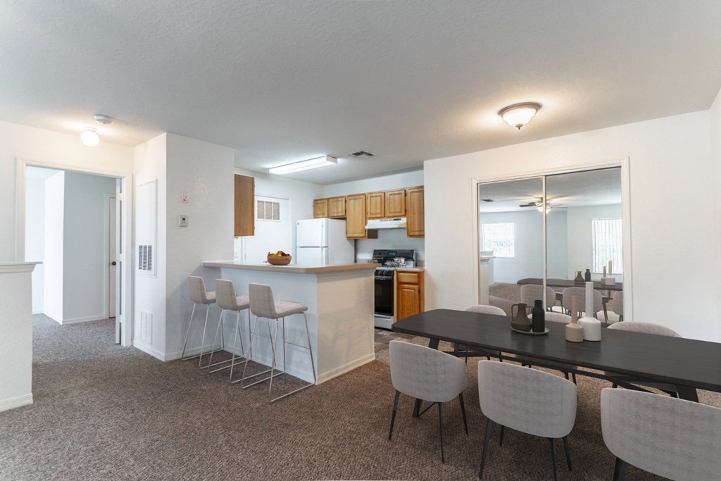 a dining area with a table and chairs and a kitchen in the background
