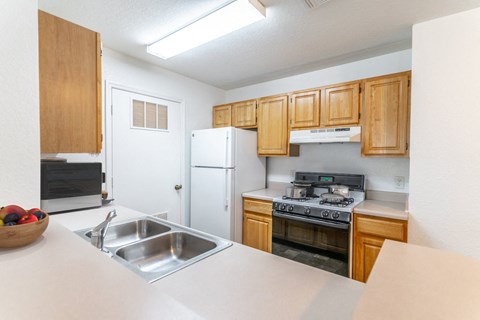 a kitchen with wooden cabinets and appliances and a sink