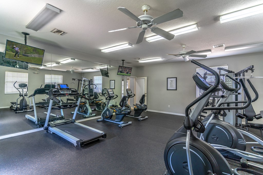a gym with cardio equipment and a flat screen tv
