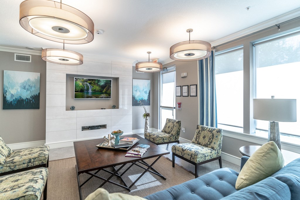a clubhouse room with couches chairs tv and a coffee table