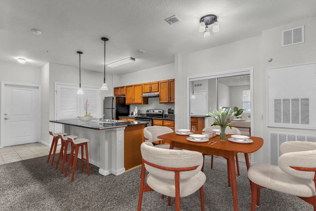 a dining area with a table and chairs and a kitchen in the background