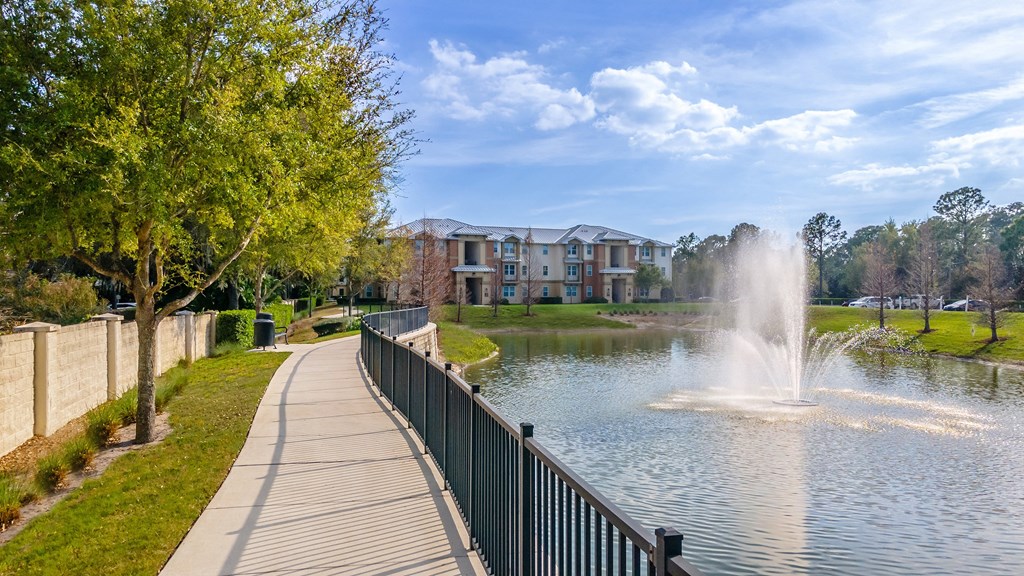 a lake with a fountain in front of a building