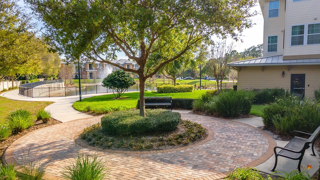 a circular brick walkway with a bench and tree in the middle of it
