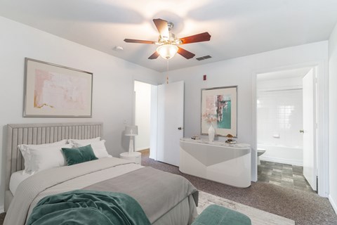 A bedroom with a bed, a bench, and a ceiling fan.