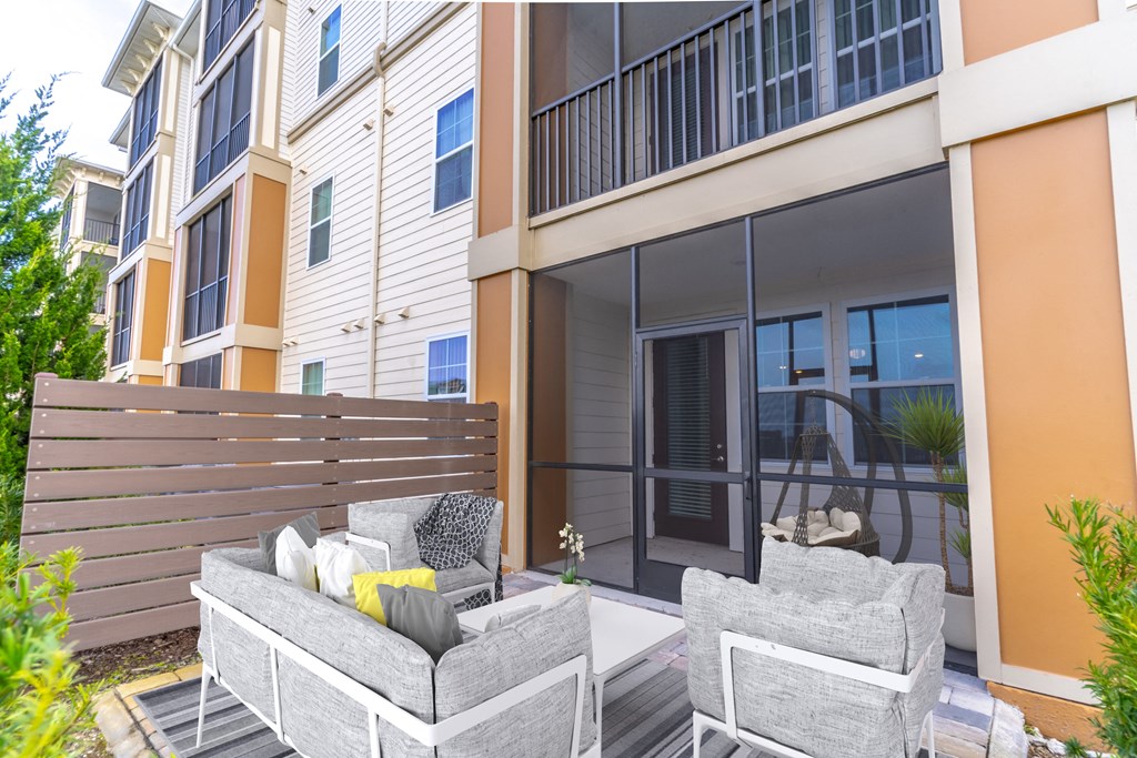 a patio with couches and chairs in front of a building