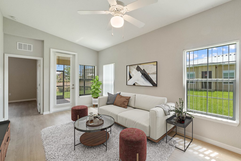 A living room with a white couch, a glass coffee table, and a ceiling fan.