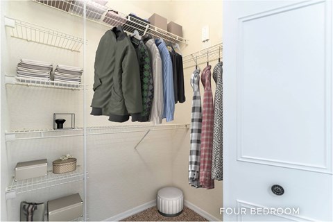 A white closet with clothes hanging and a door labeled "FOUR BEDROOM".