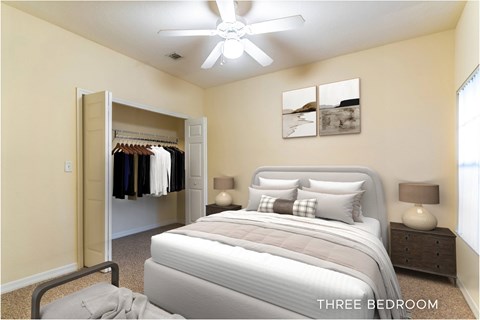 A bedroom with a large bed and a closet with clothes hanging.