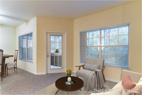 A living room with a couch, chair, and a table with a vase of flowers on it.