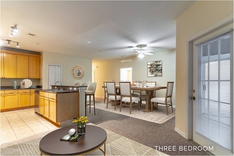 A well-lit, spacious kitchen and dining area in a three bedroom home.