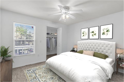 A bedroom with a large bed, a ceiling fan, and a window with a view of trees.