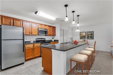 A kitchen with a refrigerator, microwave, and stove top oven.