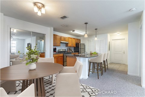 A kitchen with a table and chairs in the foreground and a bar in the background.