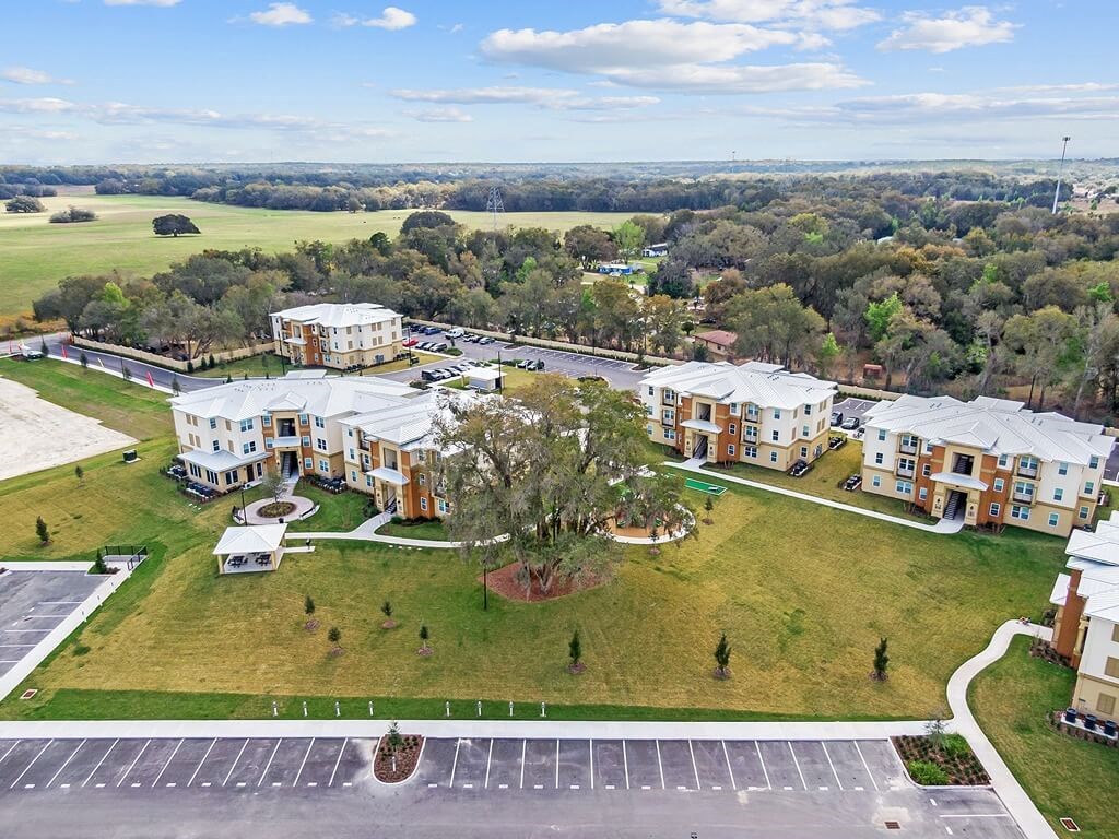 an aerial view of an apartment complex with a field and trees