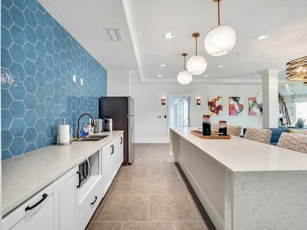 a kitchen with a long counter and a blue tile wall