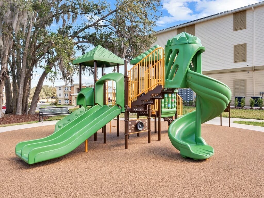 a playground with a green slide in a park