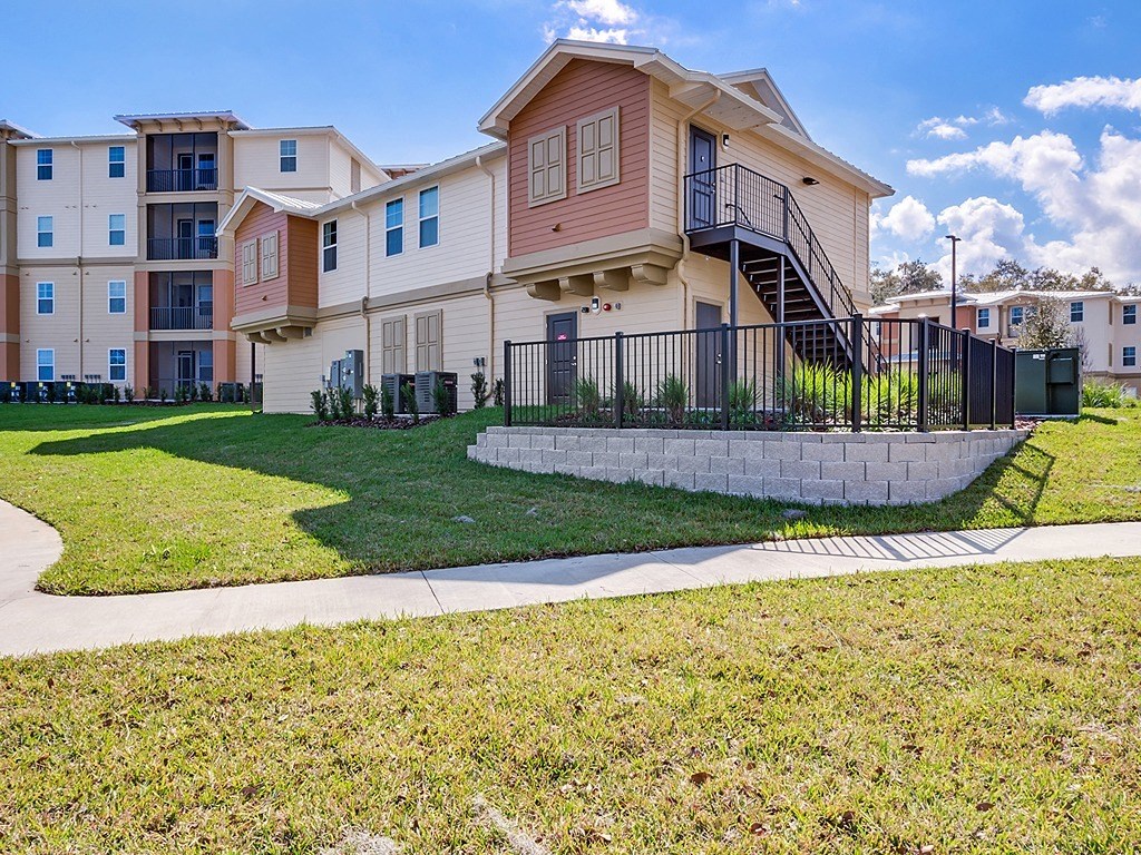 an apartment building with a lawn and sidewalk in front of it
