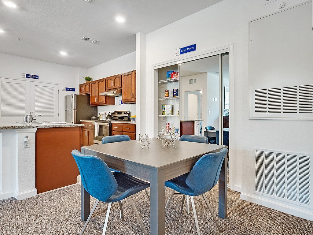 a dining room table with blue chairs in front of a kitchen