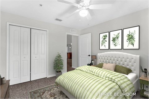 A bedroom with a bed, a ceiling fan, and a wall hanging with three framed plants.