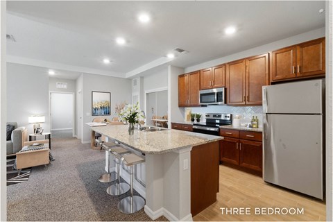 A kitchen with a bar and three bedrooms.