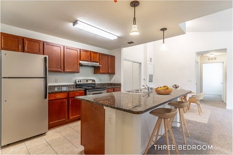 A kitchen with a refrigerator, stove, and bar stools.