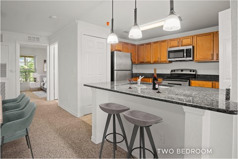 A kitchen with a black counter top and two bar stools.
