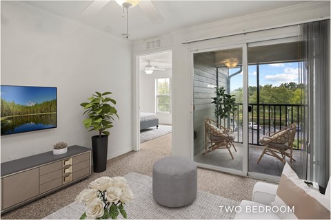 A living room with a flat screen TV and a sliding glass door leading to a balcony.