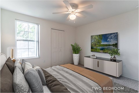 A bedroom with a bed, pillows, a ceiling fan, and a painting on the wall.