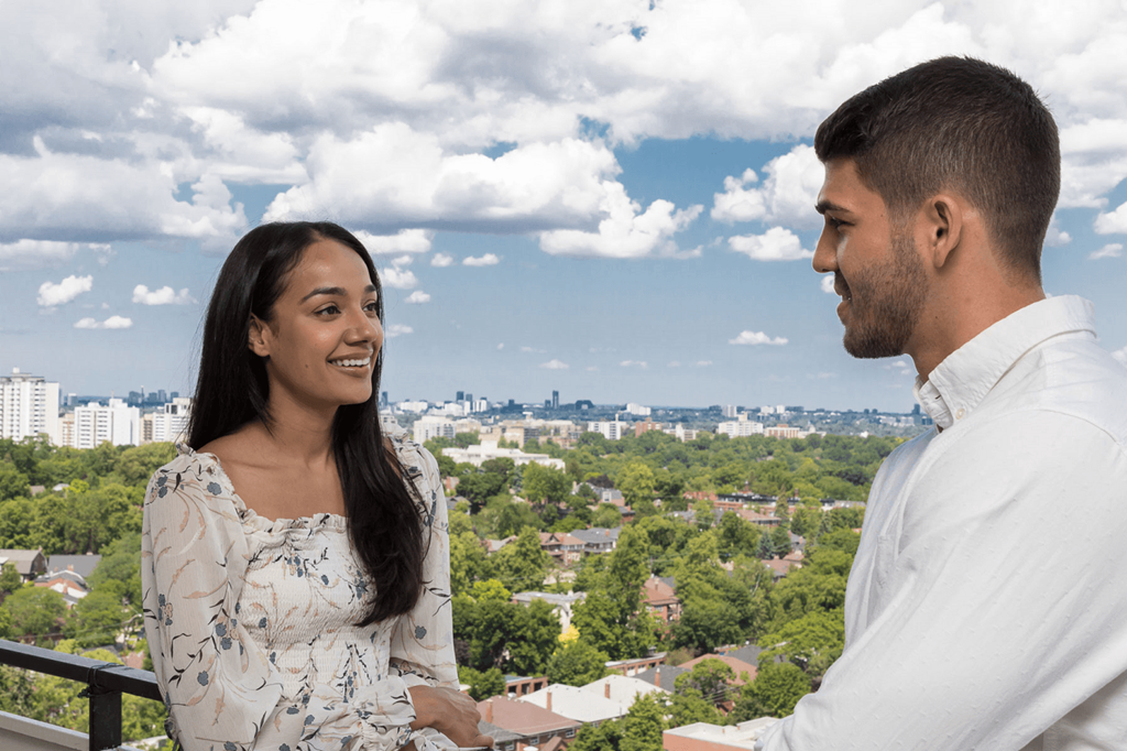 a man and woman standing on a balcony overlooking the city