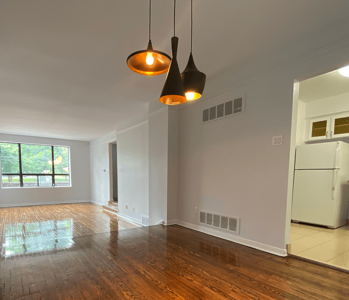 an empty living room with two lights hanging from the ceiling
