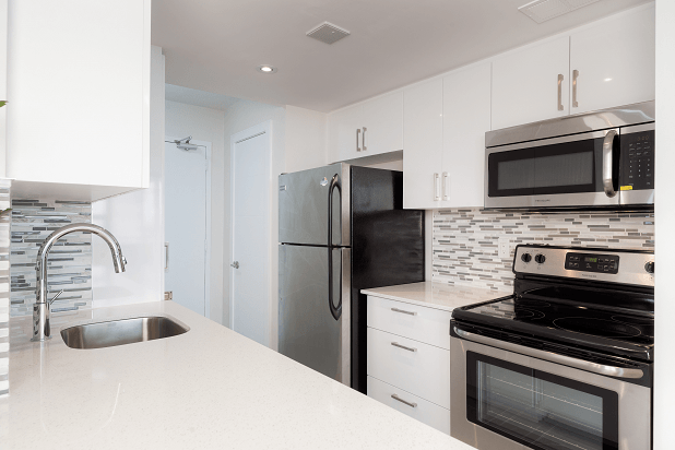 a white kitchen with stainless steel appliances and a sink