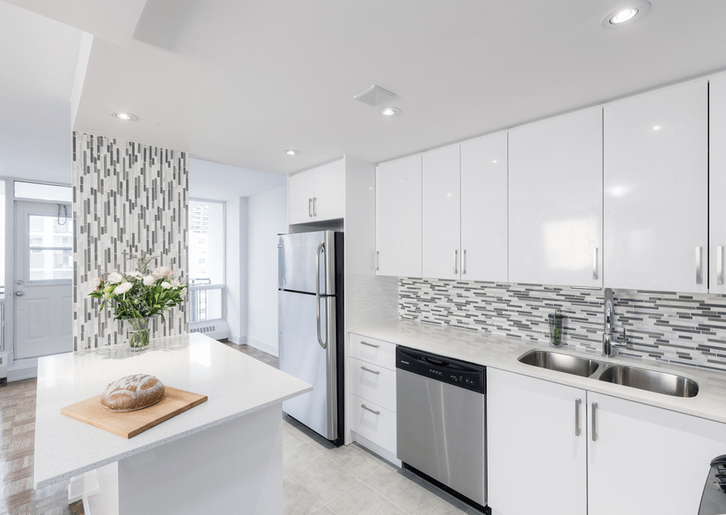 a white kitchen with stainless steel appliances and white counter tops