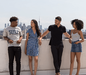 a group of people standing on a balcony with a cityscape in the background