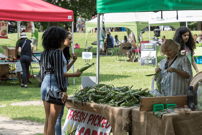 a group of women standing around a table of green beans