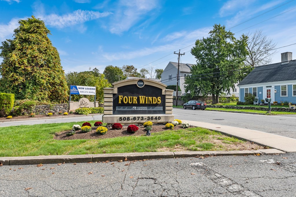 A sign for Four Winds in front of a house.