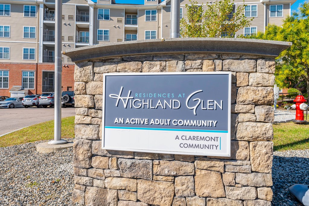 A sign for Highland Glen, an active adult community, is displayed in front of a building.