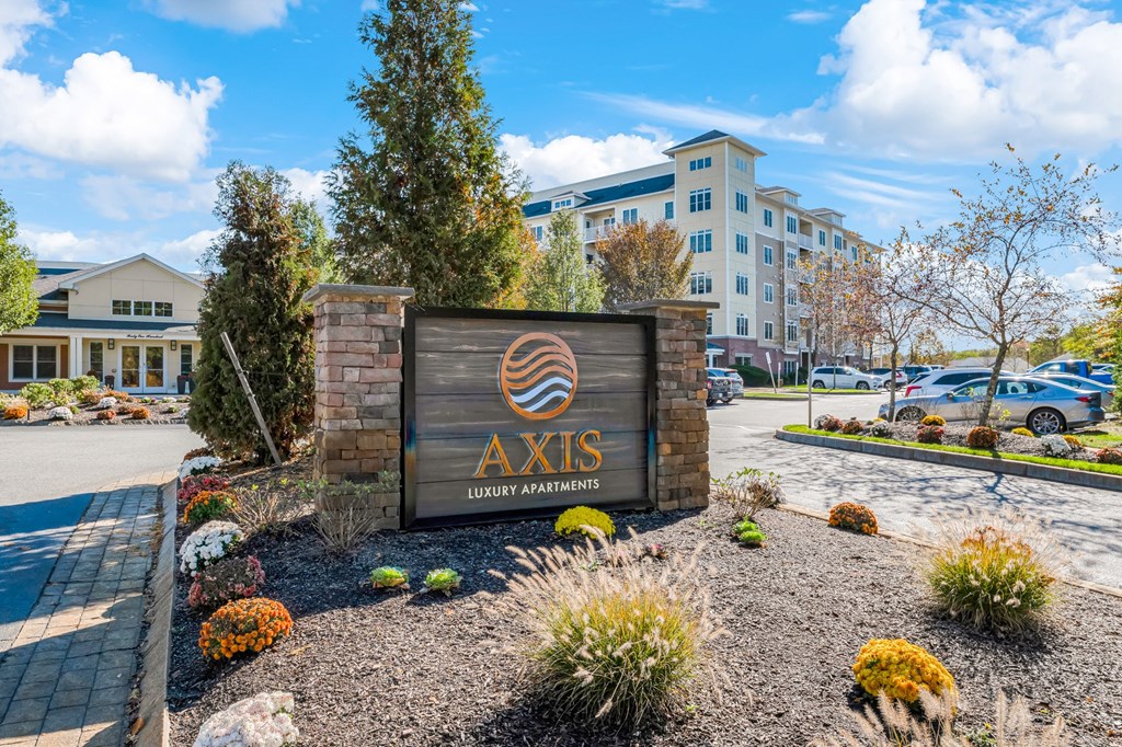 A sign for Axis Luxury Apartments is displayed in front of a building.