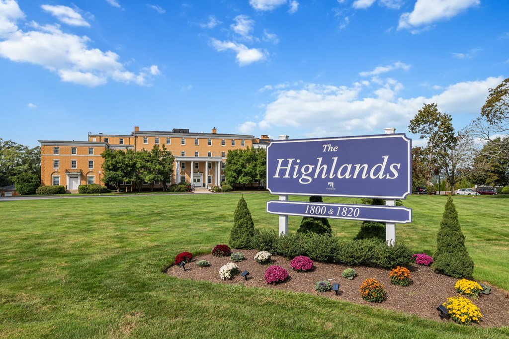 A sign for The Highlands with a building in the background.