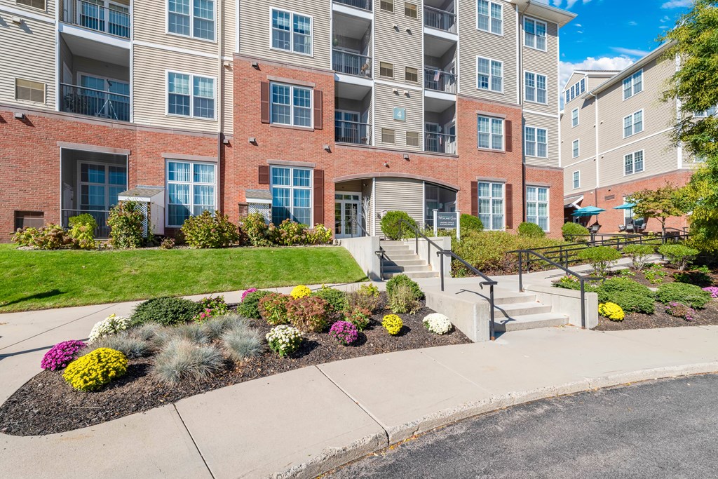 A multi-story apartment building with a landscaped front yard.