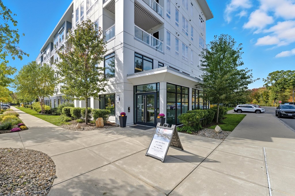 A modern building with a glass entrance and a sign in front.