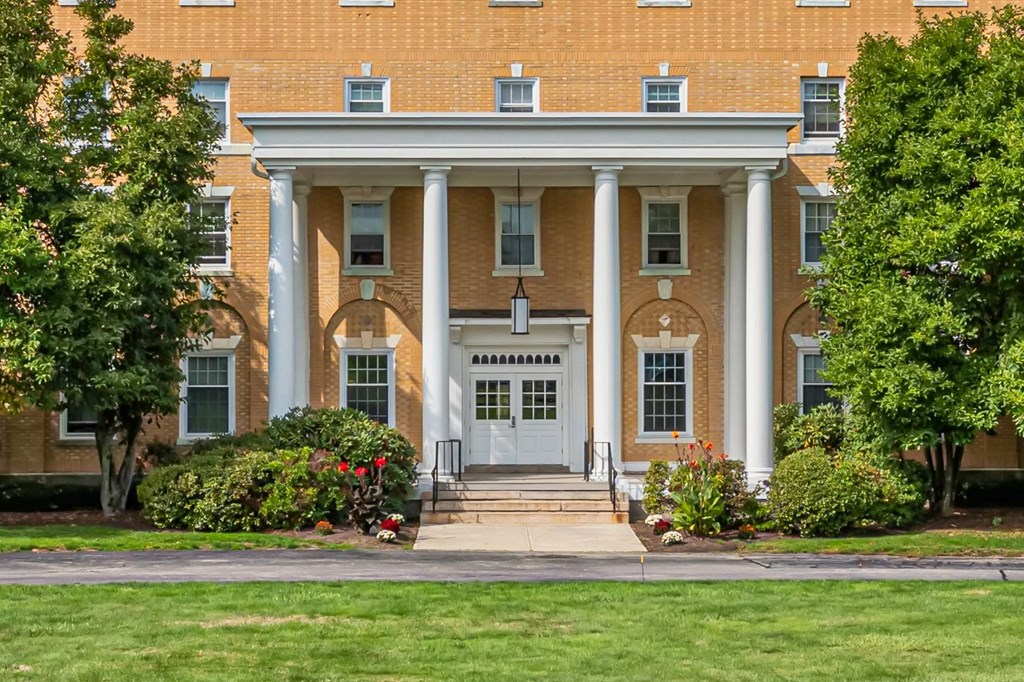A building with a white door and windows surrounded by greenery.