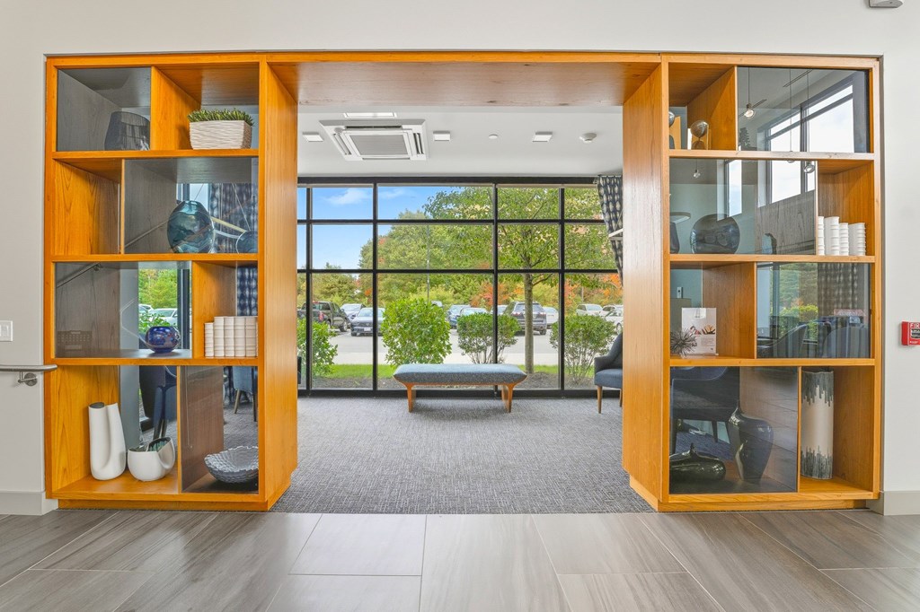 A room with a large window and a view of trees and a parking lot.