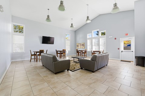A living room with a grey couch and a television on the wall.