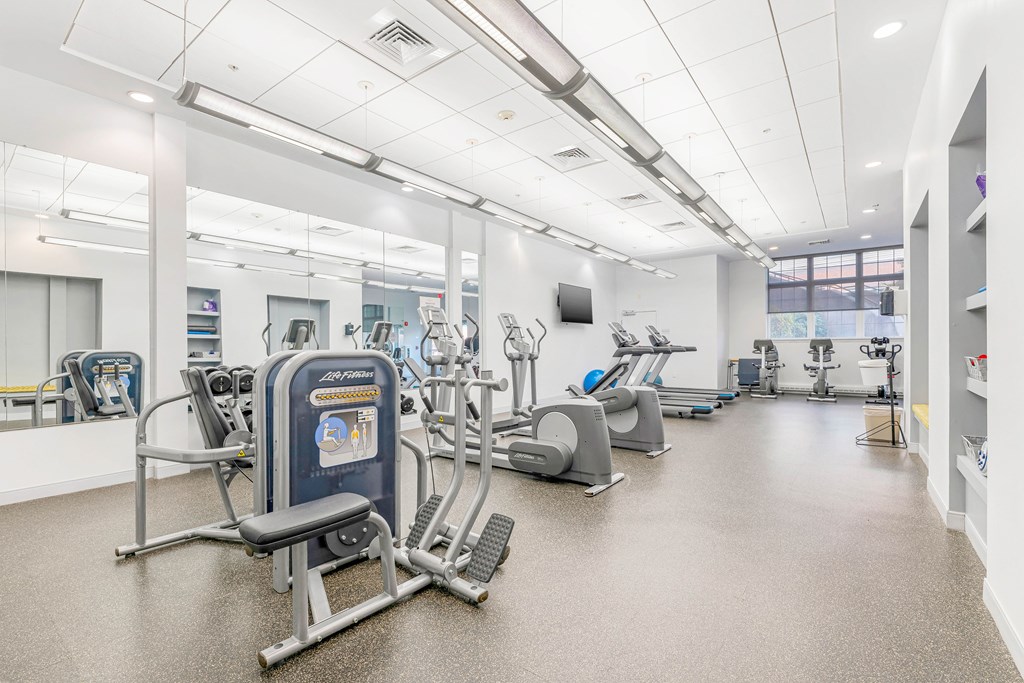 A gym with a variety of exercise equipment including treadmills, stationary bikes, and weight machines.